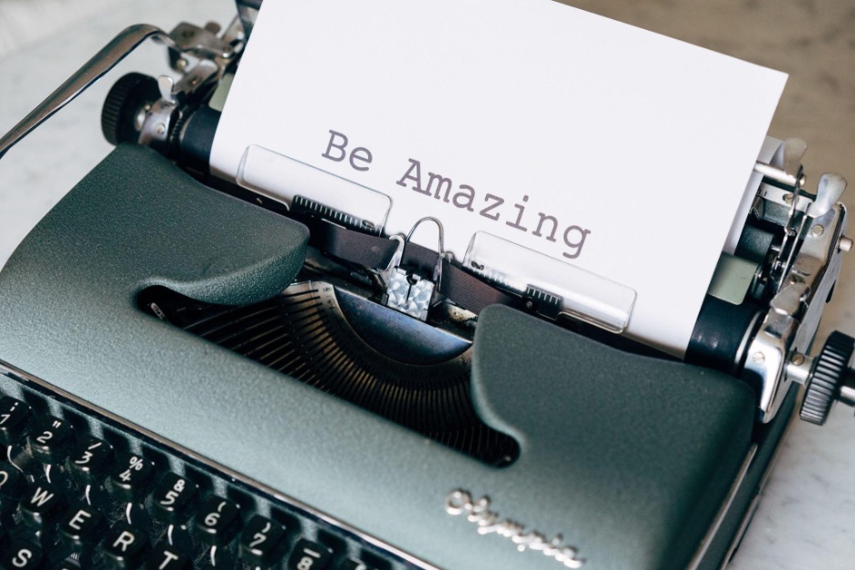 A typewriter with paper coming out that has "be amazing" typed on it.